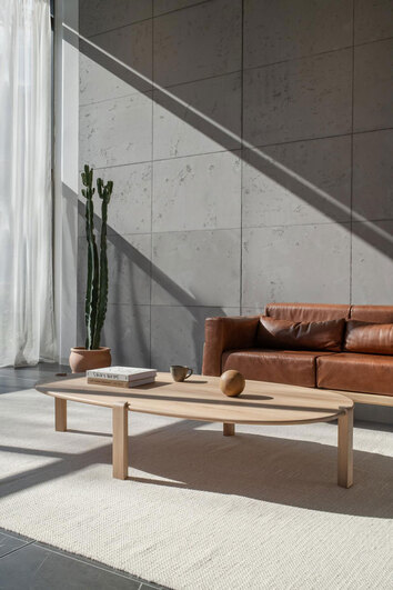 Kulin Soffbord 180x100 i vitoljad ek framför brun lädersoffa i vardagsrum