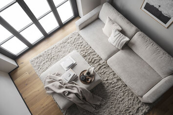 Duncan Soffa 3-Sits med Duncan Fotpall dekorerad med en pläd, en bricka och travar med böcker