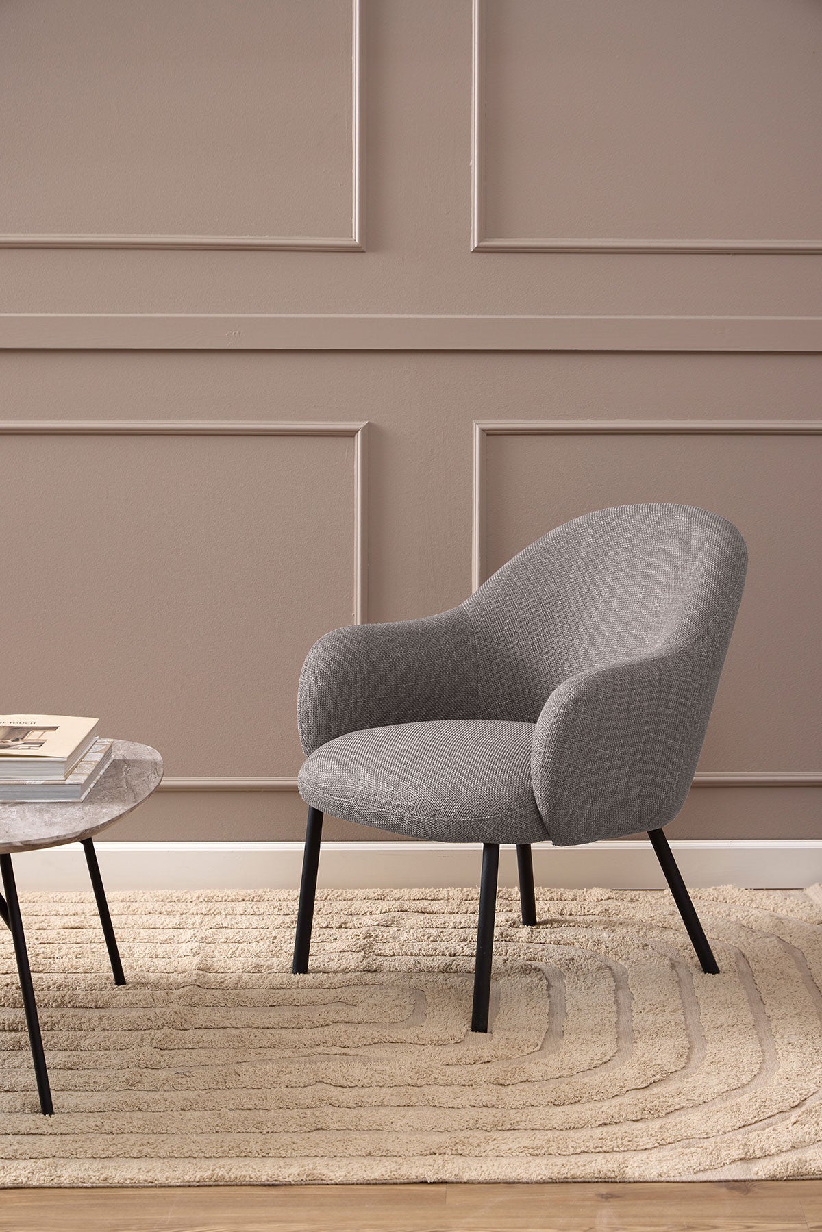 Spencer Loungefåtölj i tyget Basel Ljusgråbrun som står på en beige ullmatta