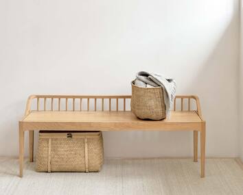 Spindle Bänk i oljad ek med en flätad korg med textilier