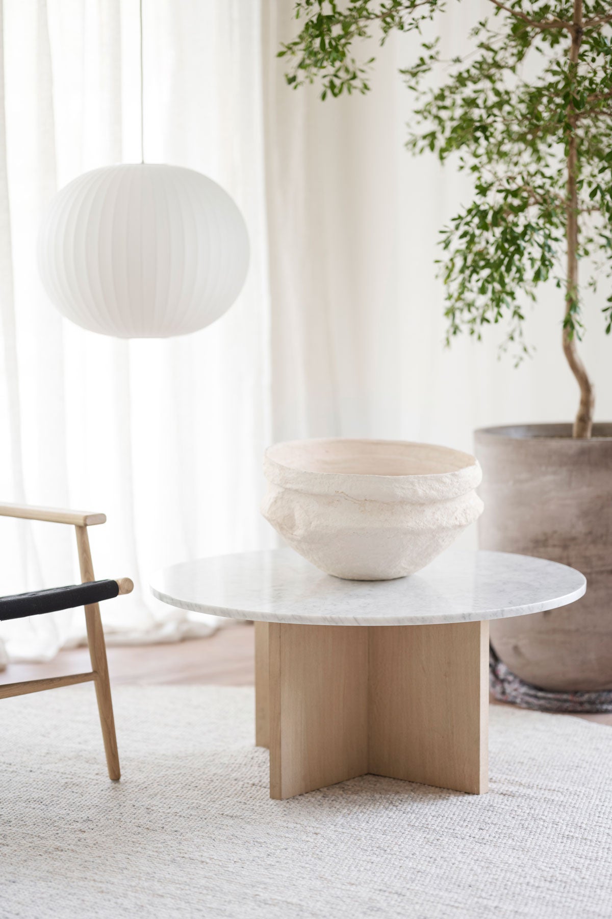 Brooksville Soffbord Runt Vit Marmor / Vitpigmenterad Ek med stor skål i keramik bredvid en krukväxt på ullmatta