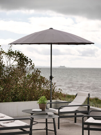 Sling Fåtölj Antracit / Vanilla under parasoll på trädäck med havsutsikt