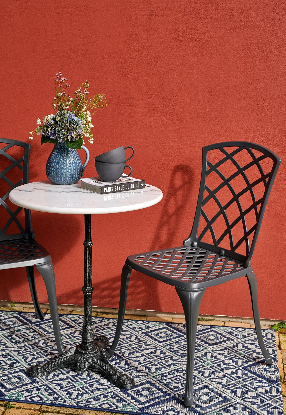 Loire Cafébord Vit med två gjutjärnsstolar vid röd husvägg