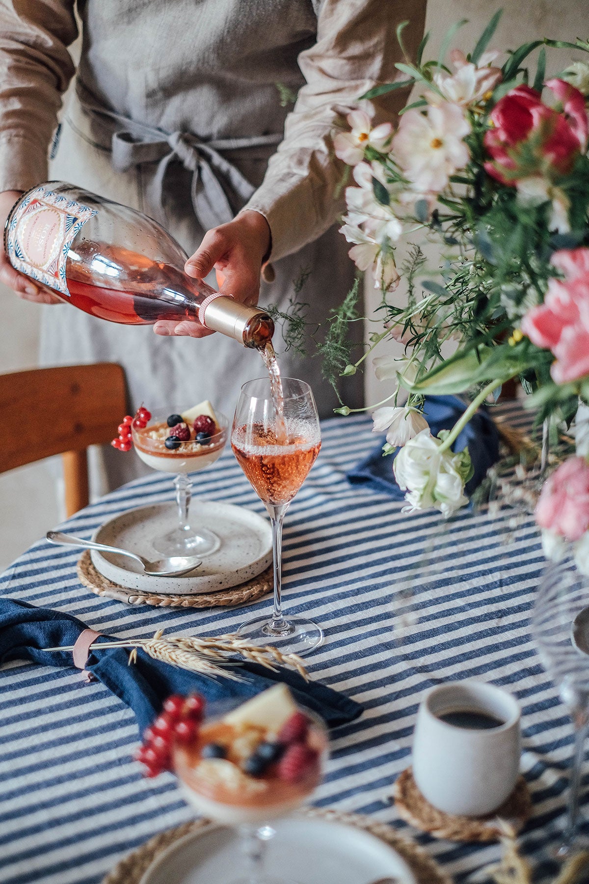 Misty Edge Bordsduk i färgen Denim Blue på matbord där en man häller upp rosé i ett vinglas