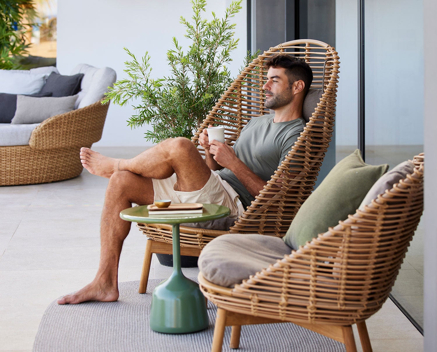 Hive Hög Fåtölj med en avslappnad man sittande med en kopp