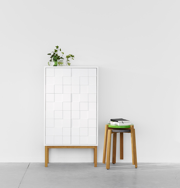 Collect 2010 Skåp. Det står flera vaser med blommor på skåpet. Bredvid skåpet står pallar staplade på varandra.