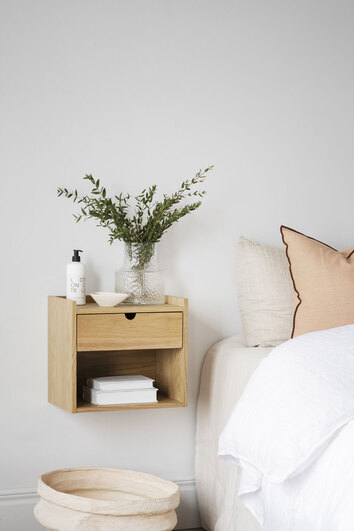 Hillmond Sängbord på vägg bredvid säng med en vas, en skål, en lotion och två böcker