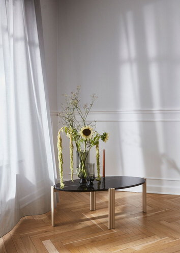 Tribus Soffbord i svart marmor. Det står en vas med vackra blommor på soffbordet.