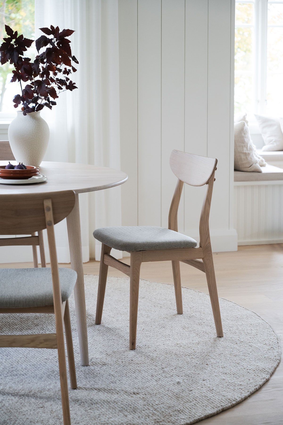 Rodham Stol i vitpigmenterad ek med gråbeige tyg vid runt matbord på matplats
