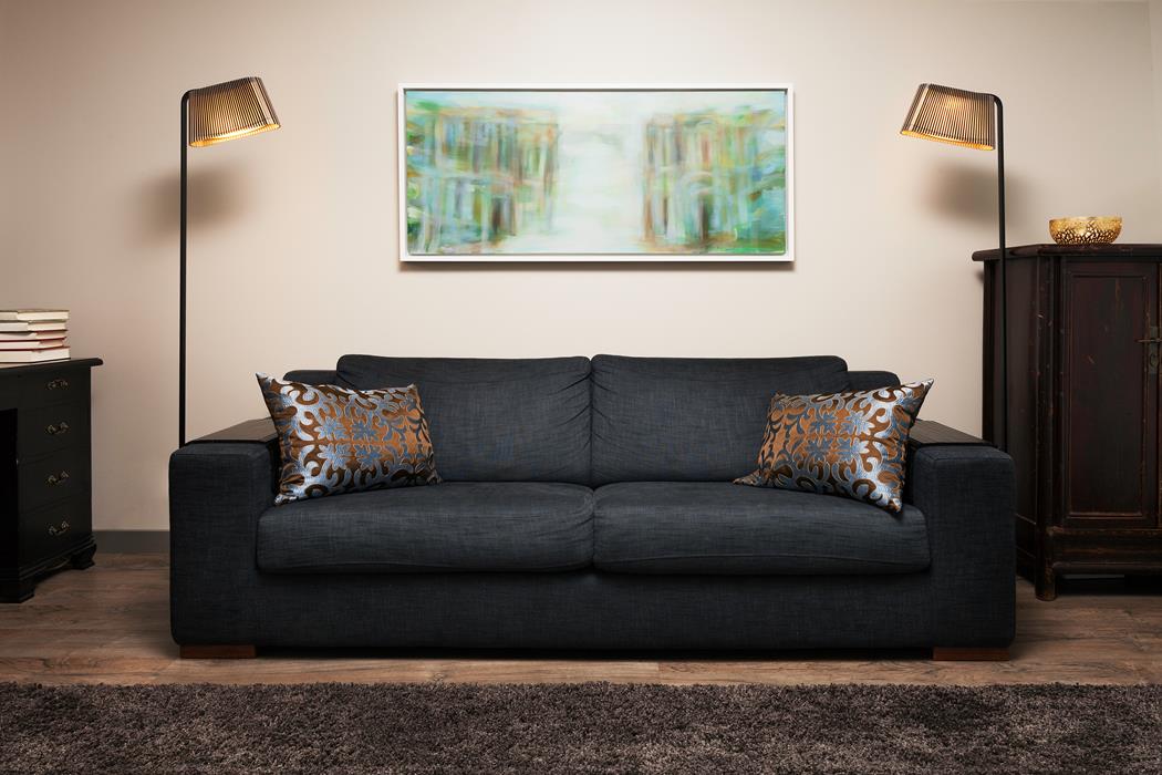 Två Owalo 7010 Golvlampa Svart på varsin sida av en svart soffa med metalliska prydnadskuddar