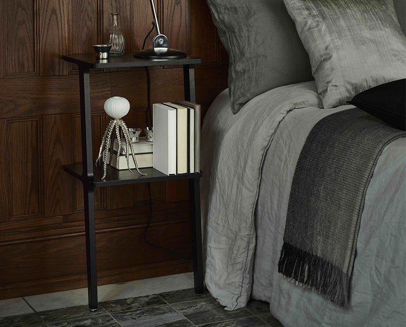 Libri Hylla i svart ask som sängbord bredvid bäddad säng