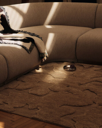 Cilla Matta i färgen Tan under en beige hörnsoffa