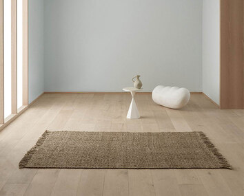 Aslak Matta Natural i tomt rum med ett sidobord och en skulptur