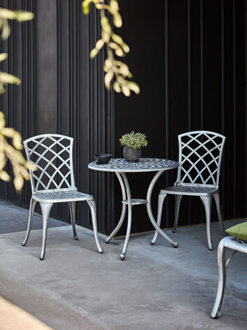 Arras Cafébord Aluminium med två stolar i aluminium vid husfasad