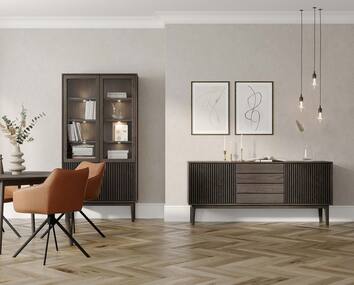 Broholm Vitrinskåp och Broholm Skänk i vardagsrum med beiga väggar och fiskbensparkett