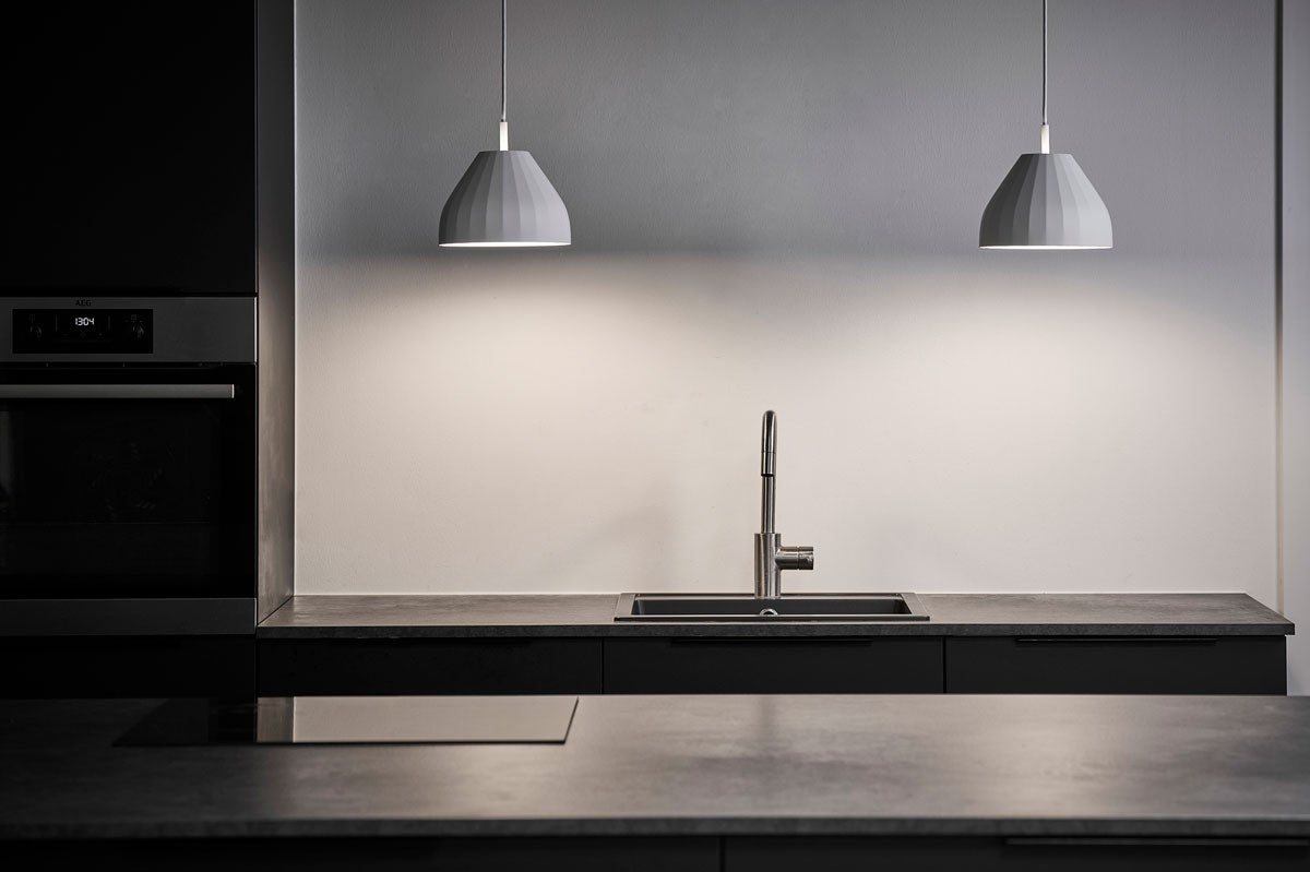 Två stycken tända Le Klint 140 Facet Pendel Vit ovanför köksbänk