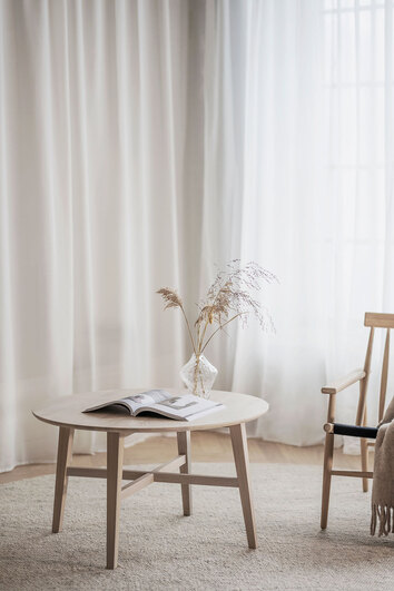 Filippa Soffbord 90 i vitpigmenterad ek. Soffbordet är dekorerat med en vas och en öppen bok.