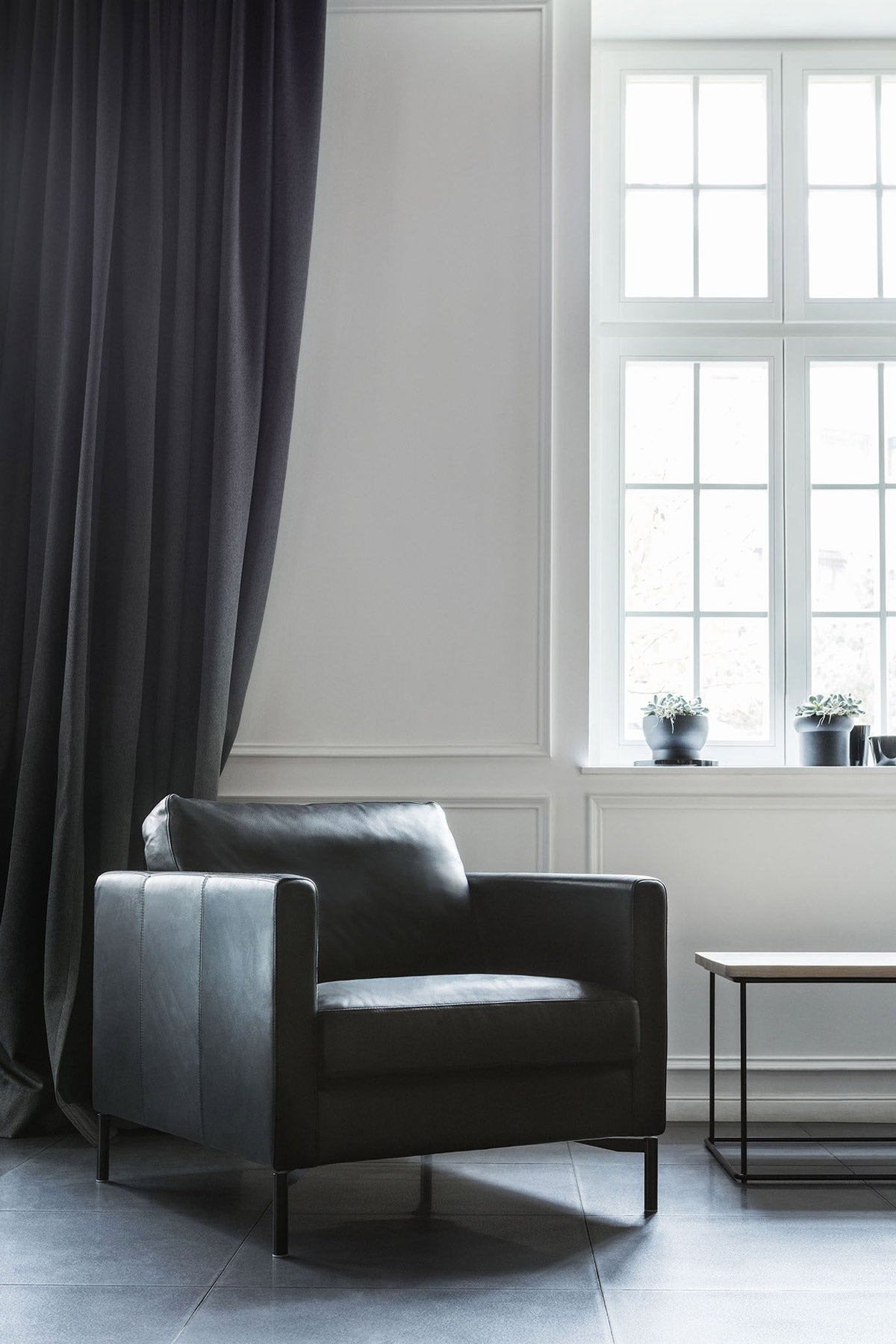 Impulse Fåtölj i läder framför en mörk gardin