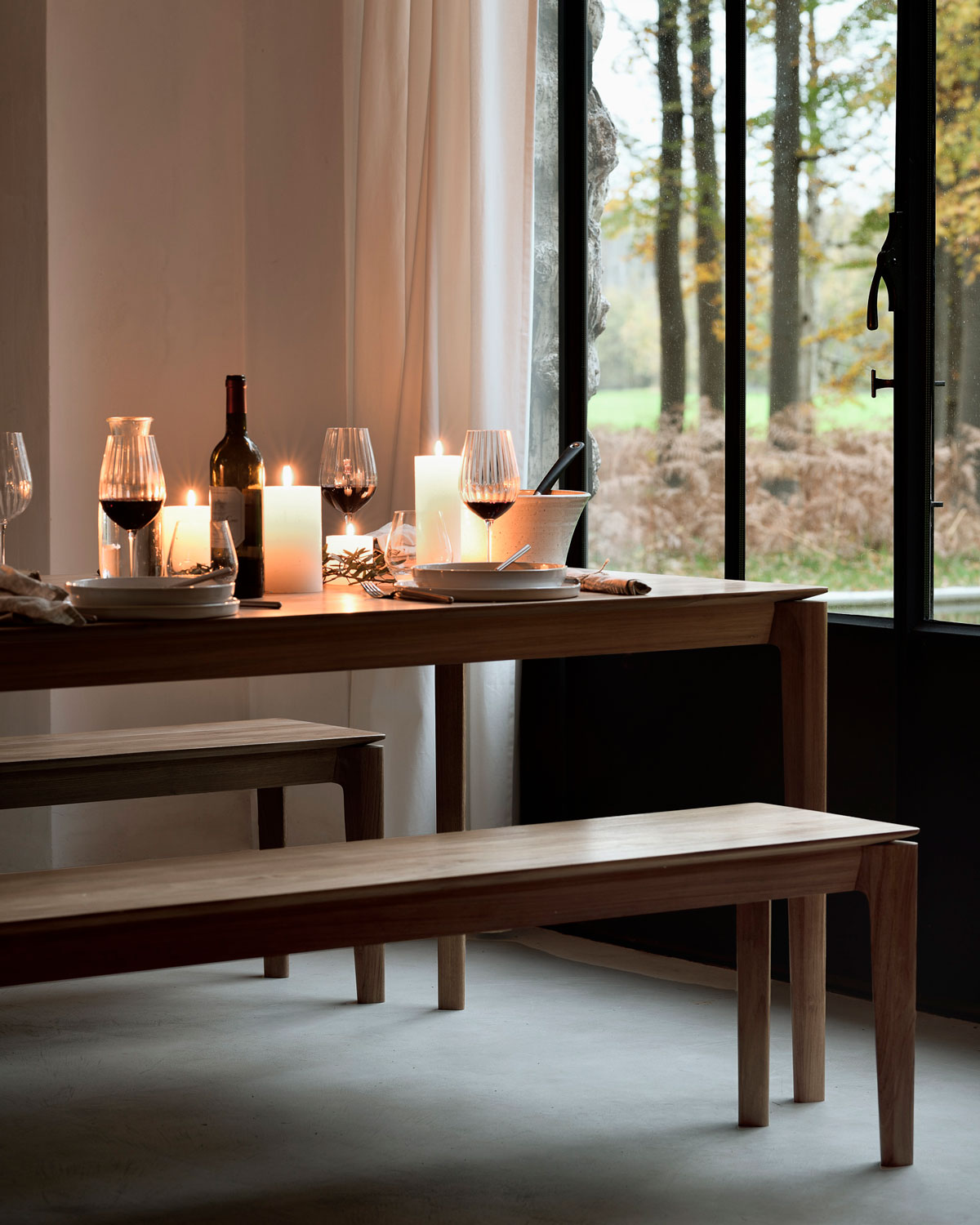 Bok Matbord och Bänk uppdukat med vin, vinglas och levande ljus med höstlandskap utanför fönstret