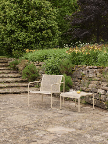 Dapple Loungestol och Dapple Loungebord 57x57 i färgen Cashmere som står på en stenig uteplats