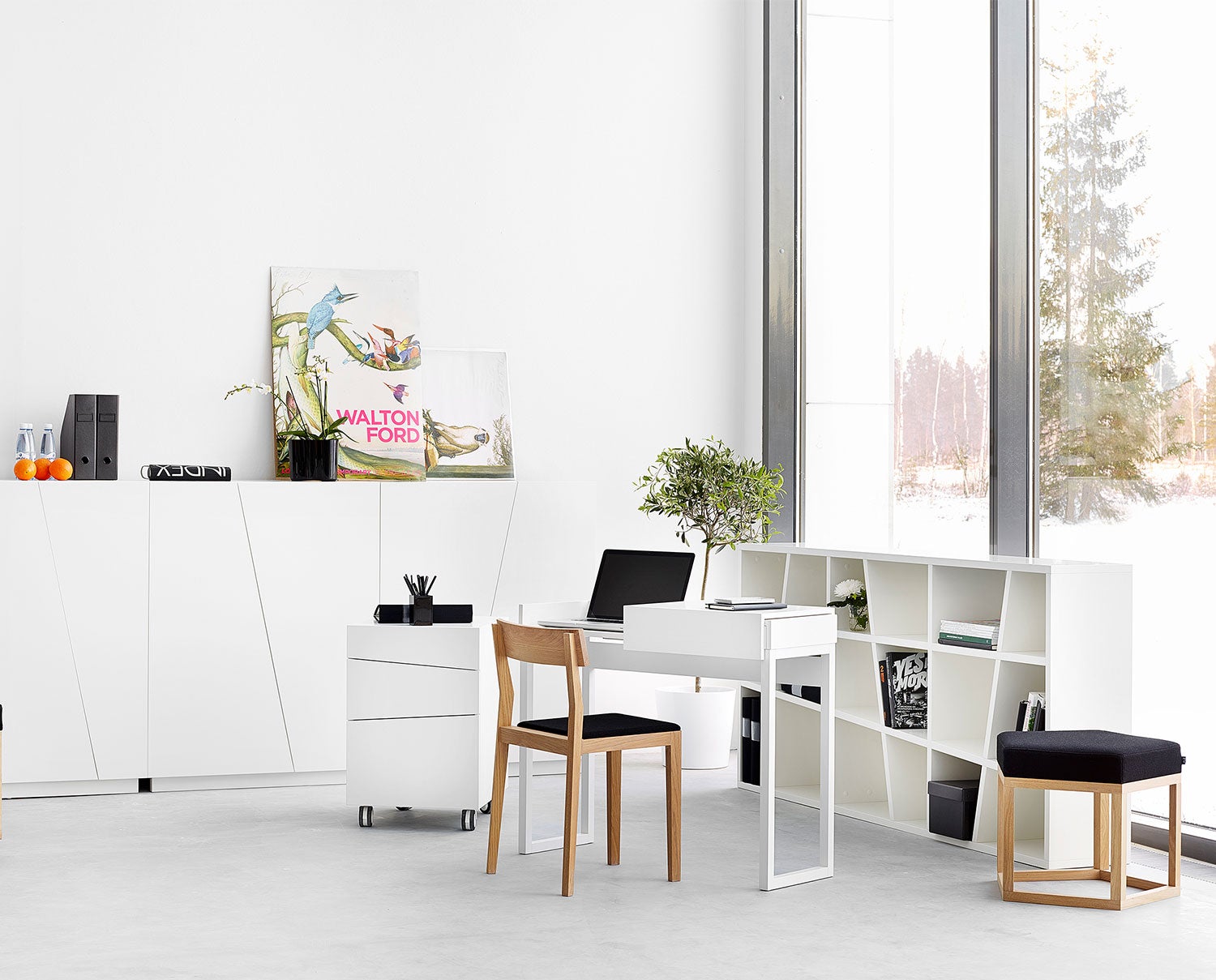 Angle hylla ståendes mot fönster och inredd böcker och dekorationsföremål.