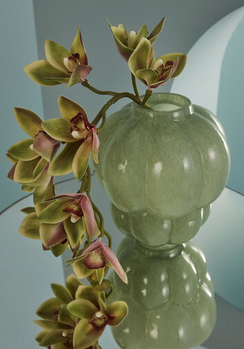 Uva Vas med en orkidékvist ståendes på ett glasbord
