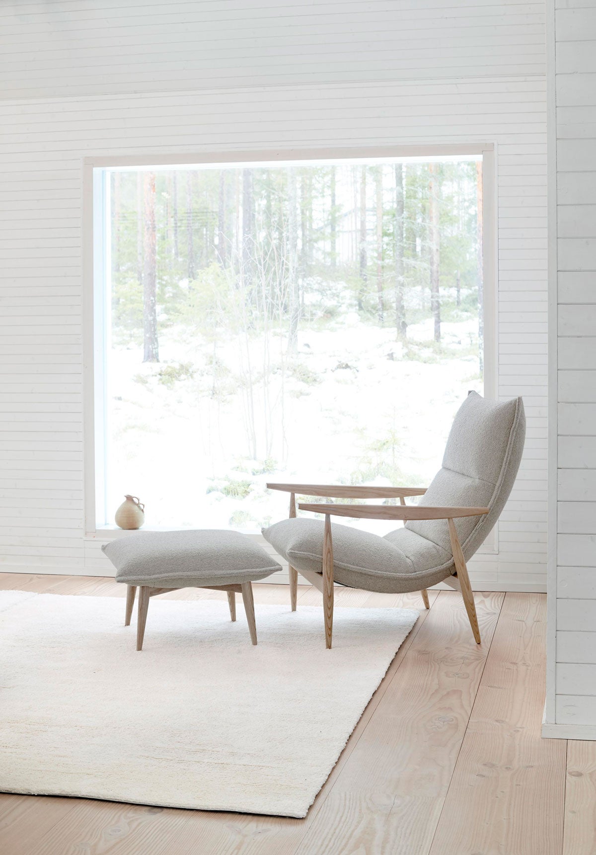 Miljöbild på fåtöljen Tao, med tillhörande fotpall. Fåtöljen är klädd i tyget Orsetto 12, med stomme i ek. 