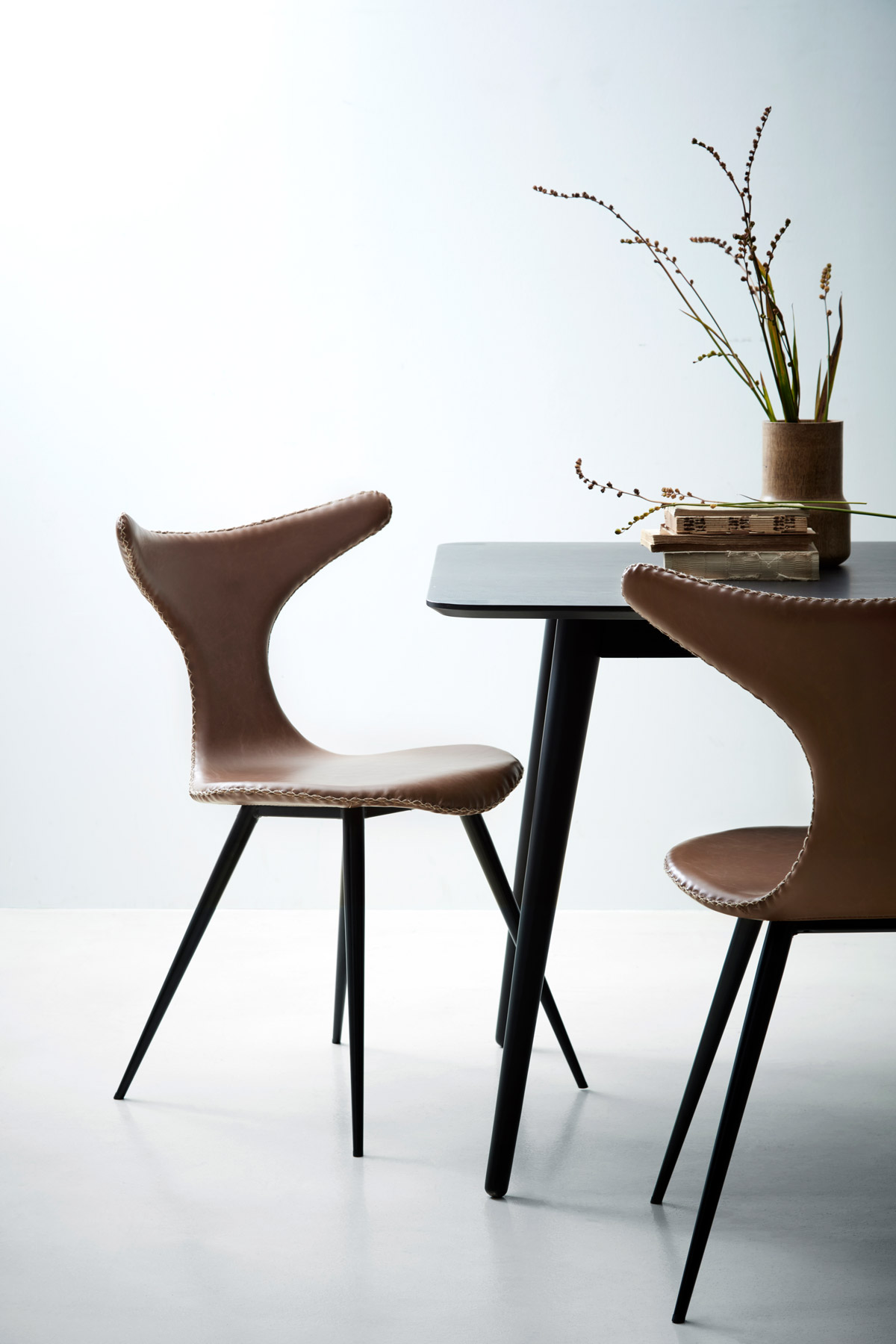 Läderstol i fina detaljer från Danform gör sig fin bredvid det svarta matbordet.