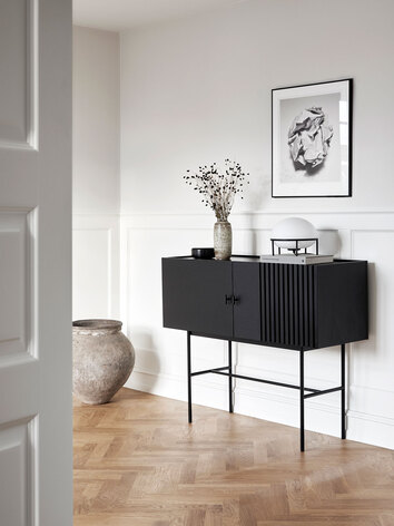 Array Sideboard Svart dekorerad med en skål, en vas med torkade blommor och en bordslampa