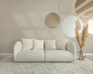 Pebble Soffa 3-sits på beige matta bredvid en vas med pampas