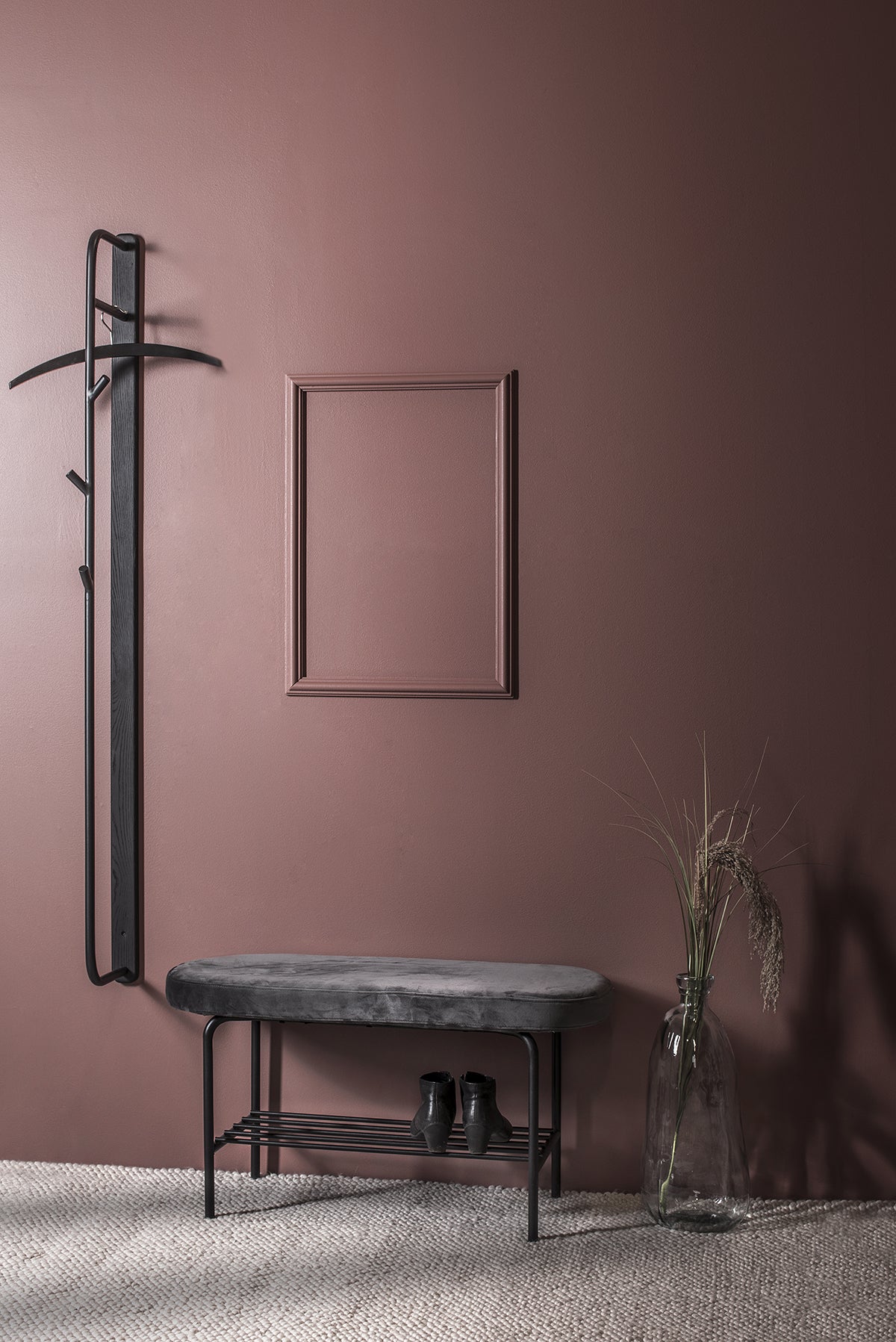 Town Hallbänk i mörkröd hall med ett par skor bredvid en klädhängare och en vas