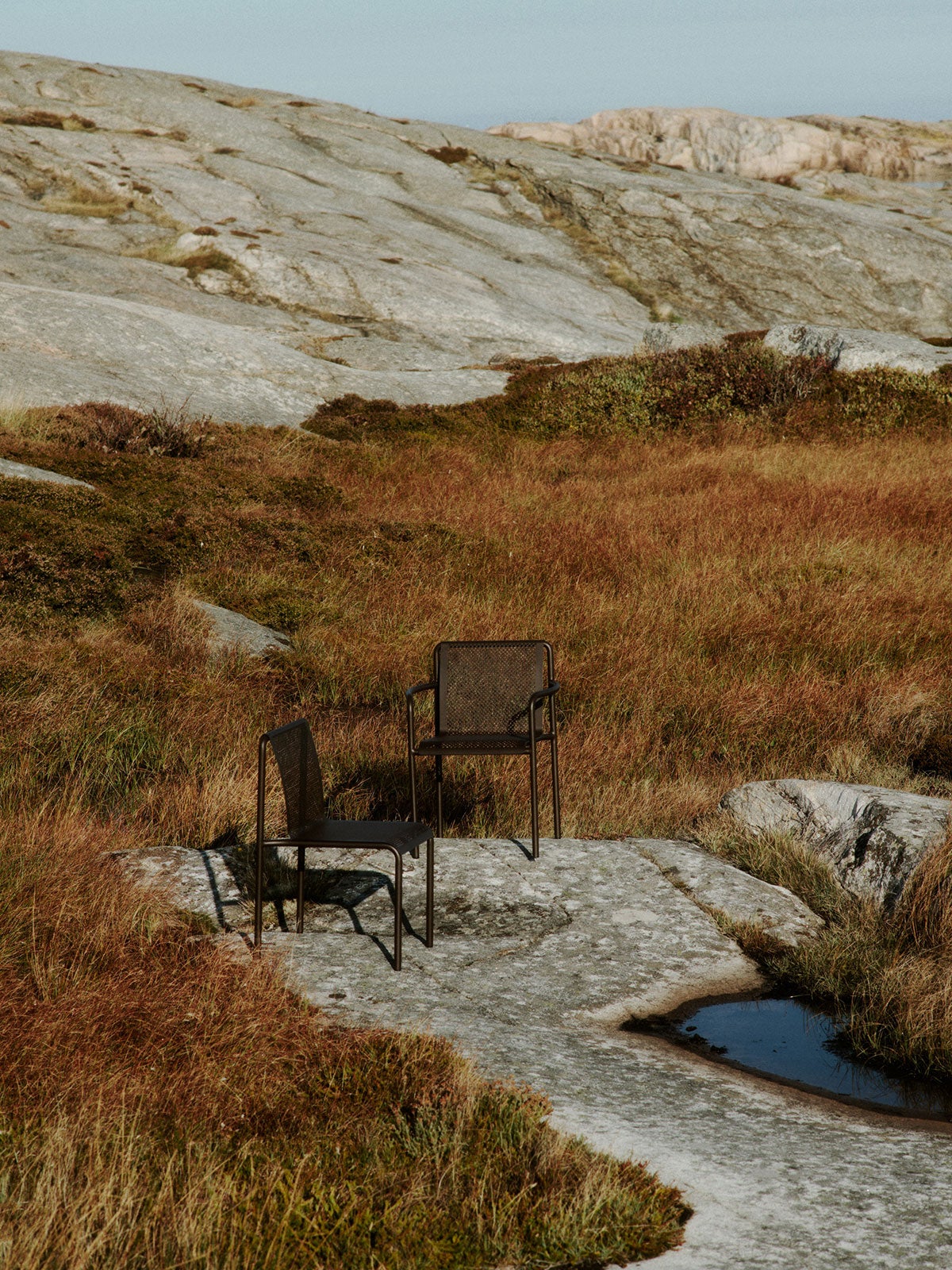Dapple Stol och Dapple Karmstol i färgen Dark Chocolate på solig berghäll