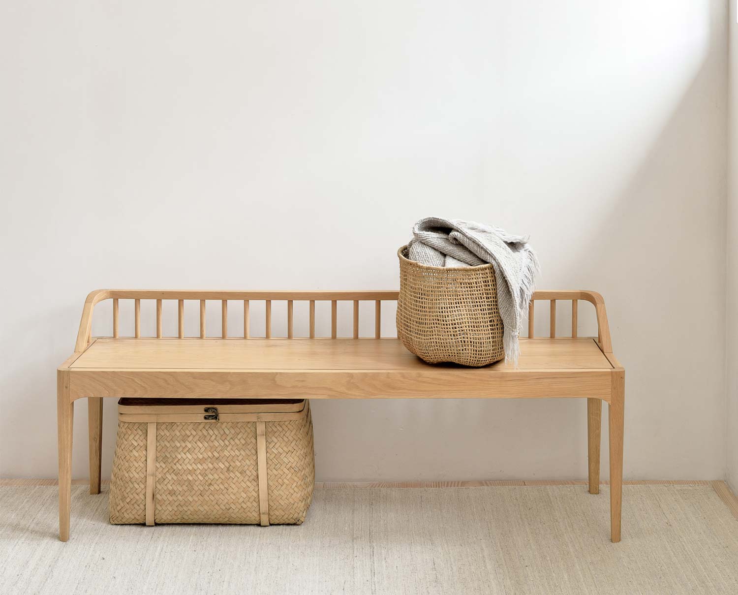 Spindle Bänk i oljad ek med en flätad korg med textilier