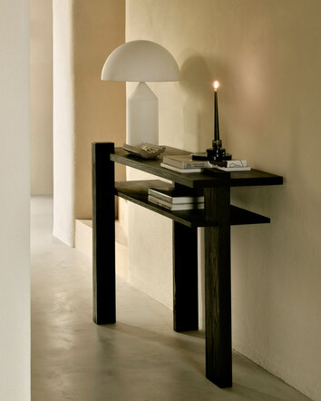Abstract Konsolbord med en vit bordslampa, ett levande ljus och dekorativa detaljer