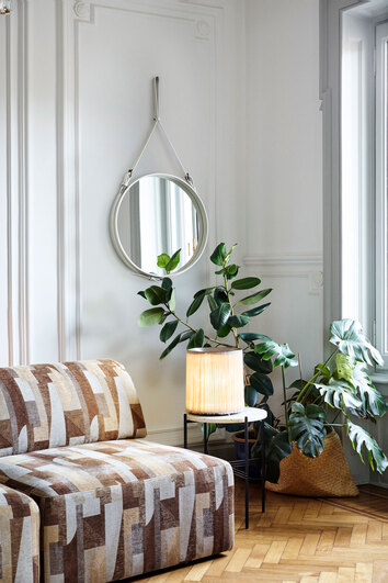Model 597 Bordslampa på sidobord intill mönstrad soffa med gröna växter
