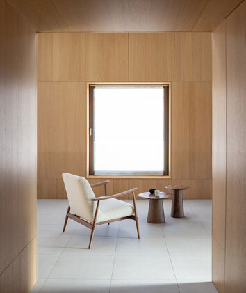 Aska Loungefåtölj i oljad valnöt i tyget Dedar Nimbus 6 i ett rum med väggar av träpaneler