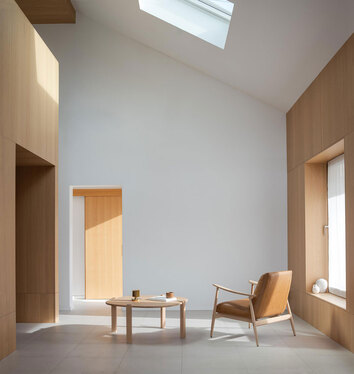 Kulin Soffbord 100x100 i vitoljad ek vid loungefåtölj i ljust, öppet rum