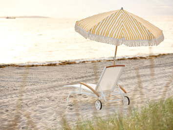 Gatsby Parasoll Gul / Vit på stranden bredvid en vit solstol