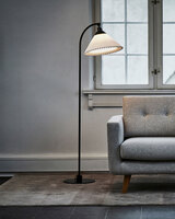 En tänd Le Klint 368 Golvlampa bredvid soffa