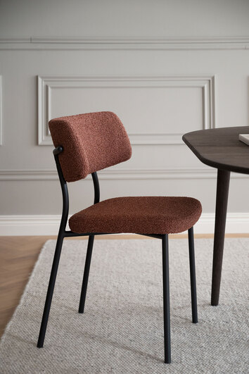 Herbster Stol med rött tyg och svarta metallben vid ett mörkbrunt matbord i matsal