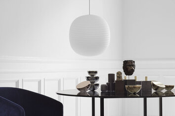 Lantern Pendel som hänger ovanför ett runt matbord fyllt med dekorativa detaljer