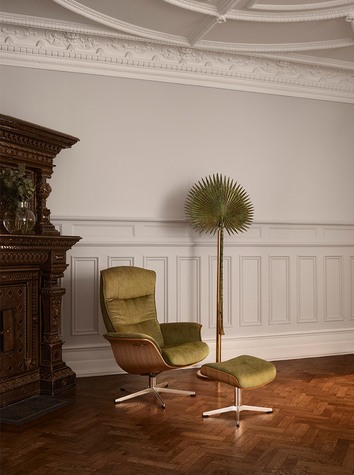 Prime Fåtölj klädd i olivfärgat tyg i ett stort vardagsrum med sekelskiftes panel. 