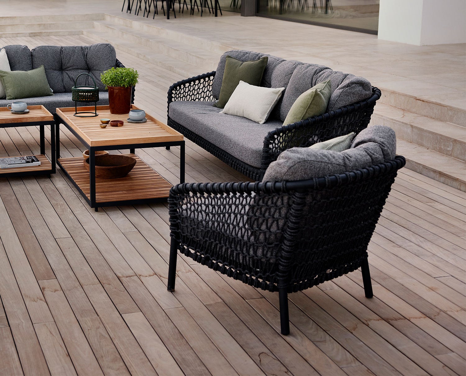 Ocean Loungefåtölj och Loungesoffa i tyget Dark Grey, stående tillsammans på ett trädäck