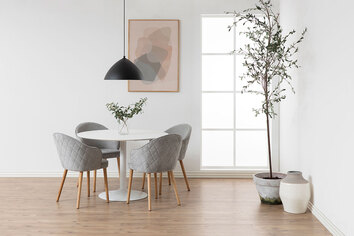 Ibiza Matbord i vit MDF med fyra matstolar i grått tyg som står i en ljus matsal