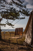 Fåtölj A2 i teak vid vitt tält i solnedgång med hav i bakgrunden