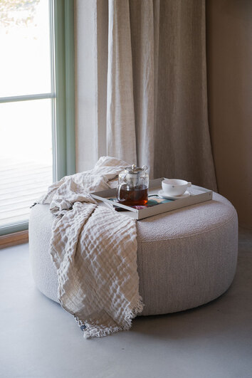 Joplin Sittpuff 90 i tyget Alice 01 Ljusbeige med en pläd och en bricka med en tekanna och tekopp