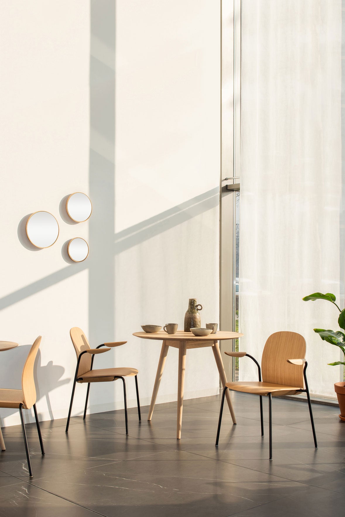 Två stycken Book Karmstol med träsits i naturlackad ek vid ett runt bord i restaurang