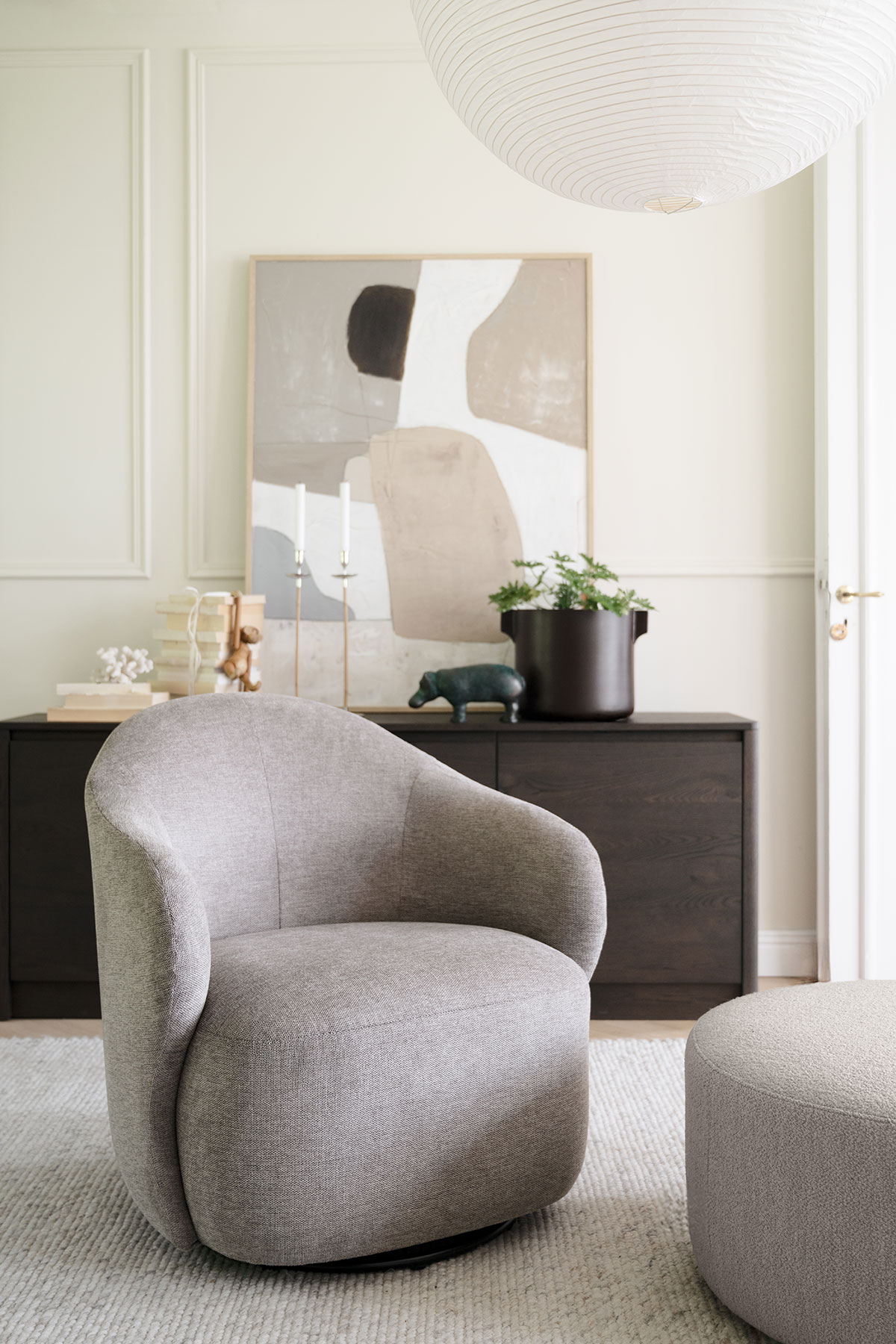 Chapeltown Snurrfåtölj i tyget Brenda 34 Beige framför ett sideboard i vardagsrum