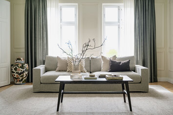 Filippa Soffbord 130 i brun ek i vardagsrum med en grå soffa