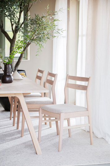 Kerwin Stol i vitpigmenterad ek med ljusbeige tyg runt ett rektangulärt matbord i matsal